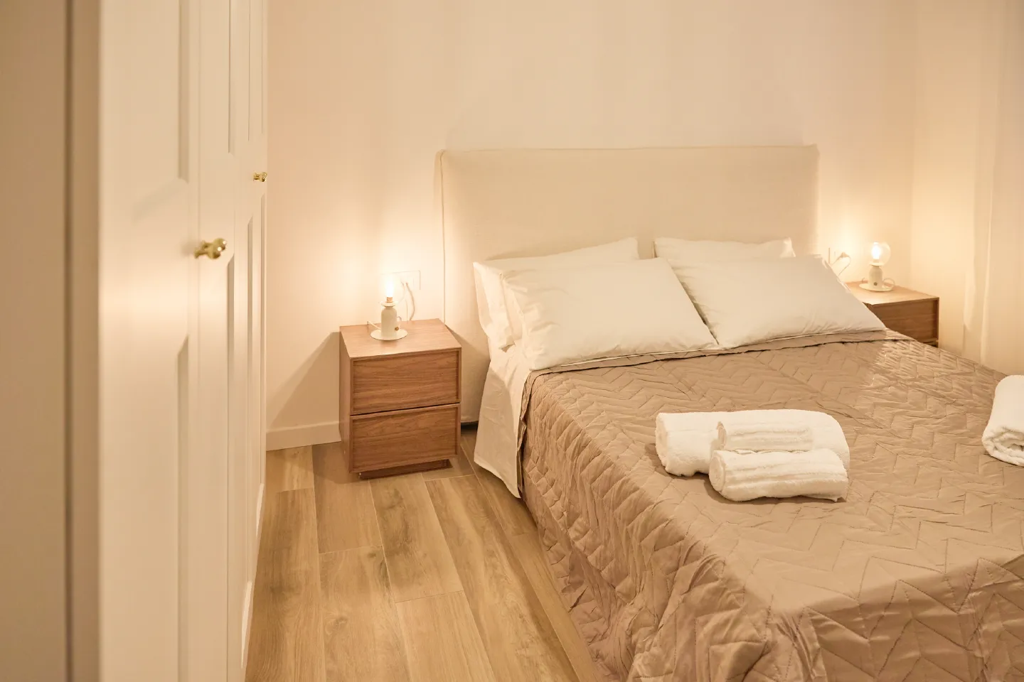 Camera da letto matrimoniale dell'Appartamento Giovanna a Chioggia con comodino in legno, lampada di design e armadio a muro.